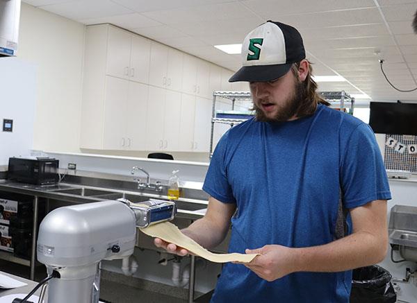 Student making pasta in a pasta maker.